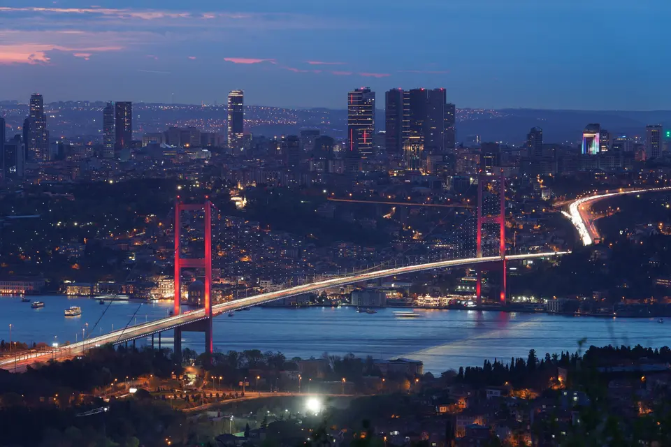 The Bosphorus Bridge lit red at night, with Istanbul spreading out behind it